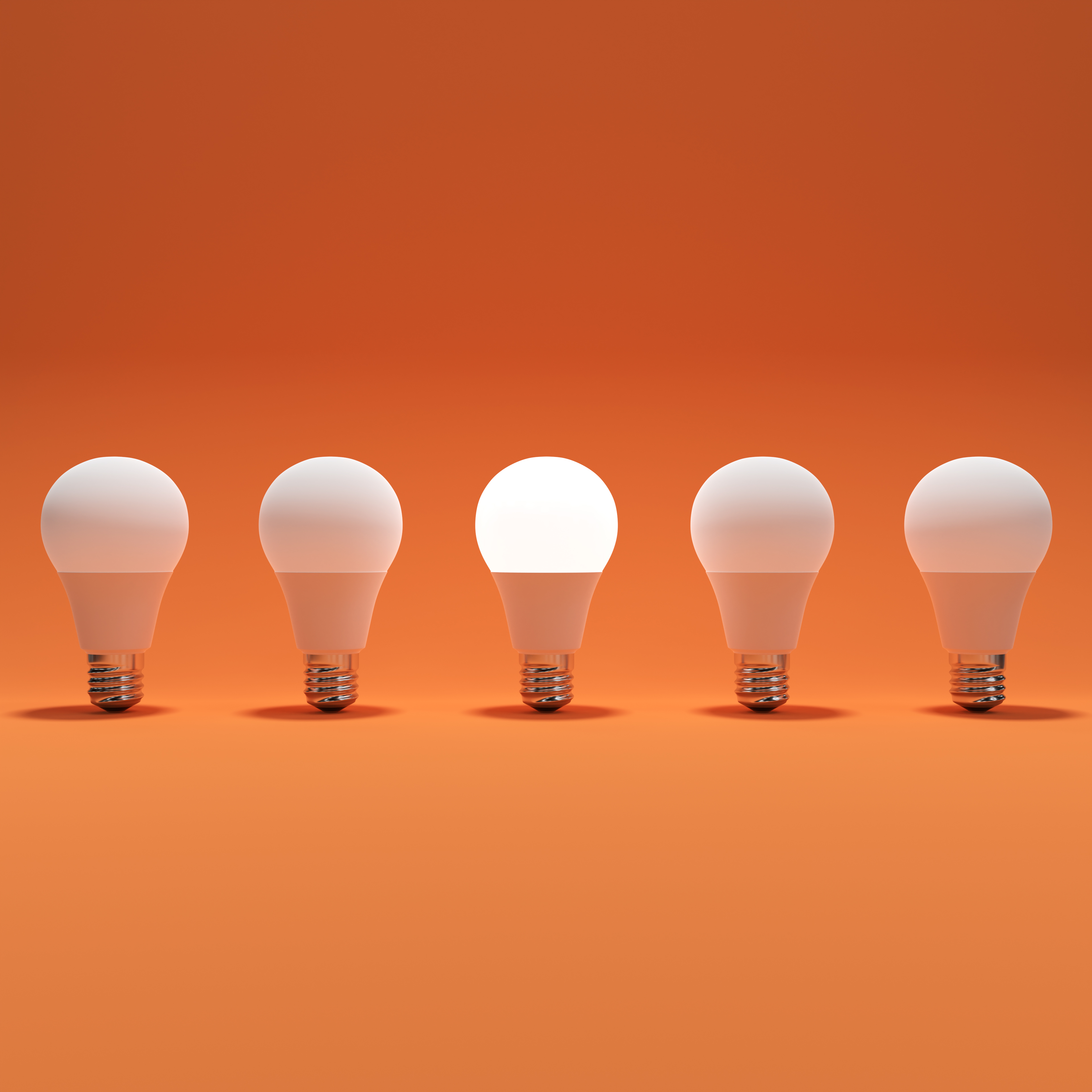 Five Lightbulb and One Glowing Lightbulb with Orange Background